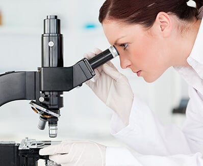 scientist looking through a microscope in a lab