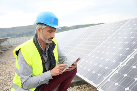 Mature engineer on building roof checking solar panels